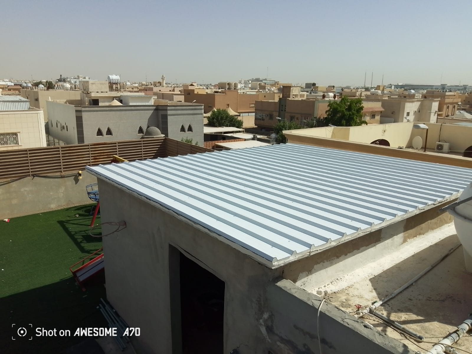 سقف معدني منفّذ فوق غرفة سطح مطلة على حي سكني من تنفيذ عالم الظل الأول