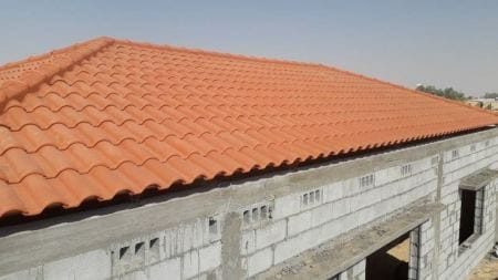 سقف قرميد أحمر منفّذ فوق مبنى قيد التشطيب من أعمال عالم الظل الأول